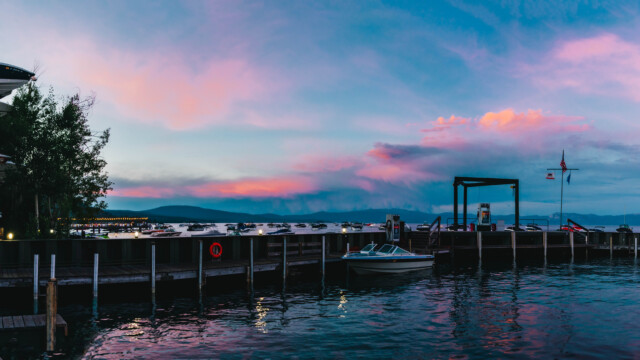 Sunset at the harbor with boats in the water as well as stored on land. Colorful sunset in the background. Sunset looking over marina, boats in the water and colorful clouds in the sky