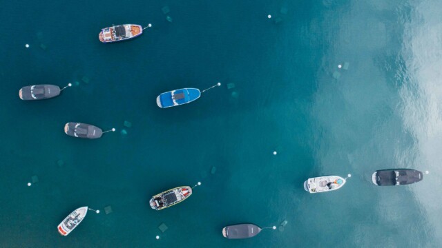 Tahoe from above — boats on the buoys, water like glass. Aerial top-down view of boats moored on buoys in the crystal-clear teal waters of Lake Tahoe.